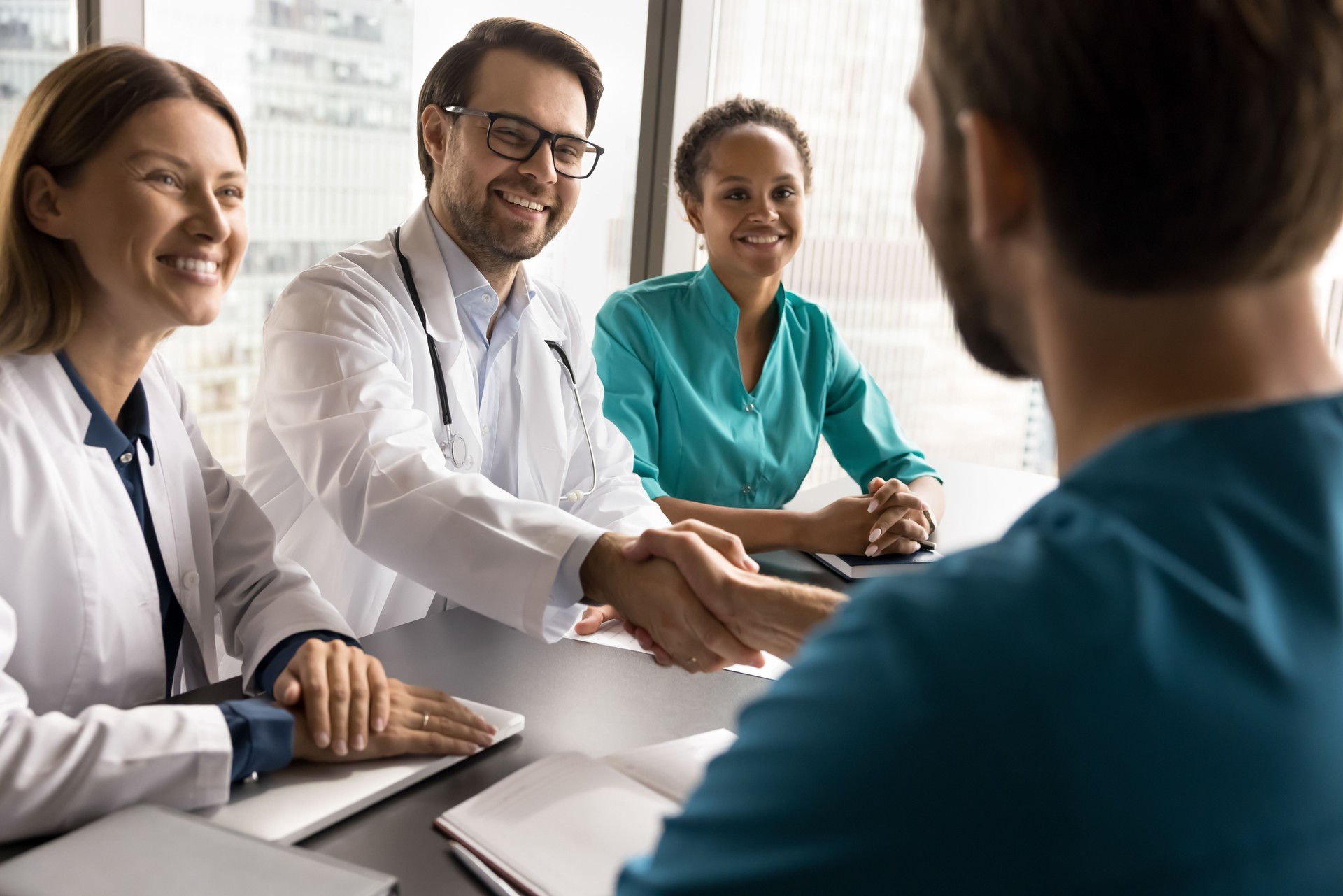 Diverse medical workers shaking hands at conference table